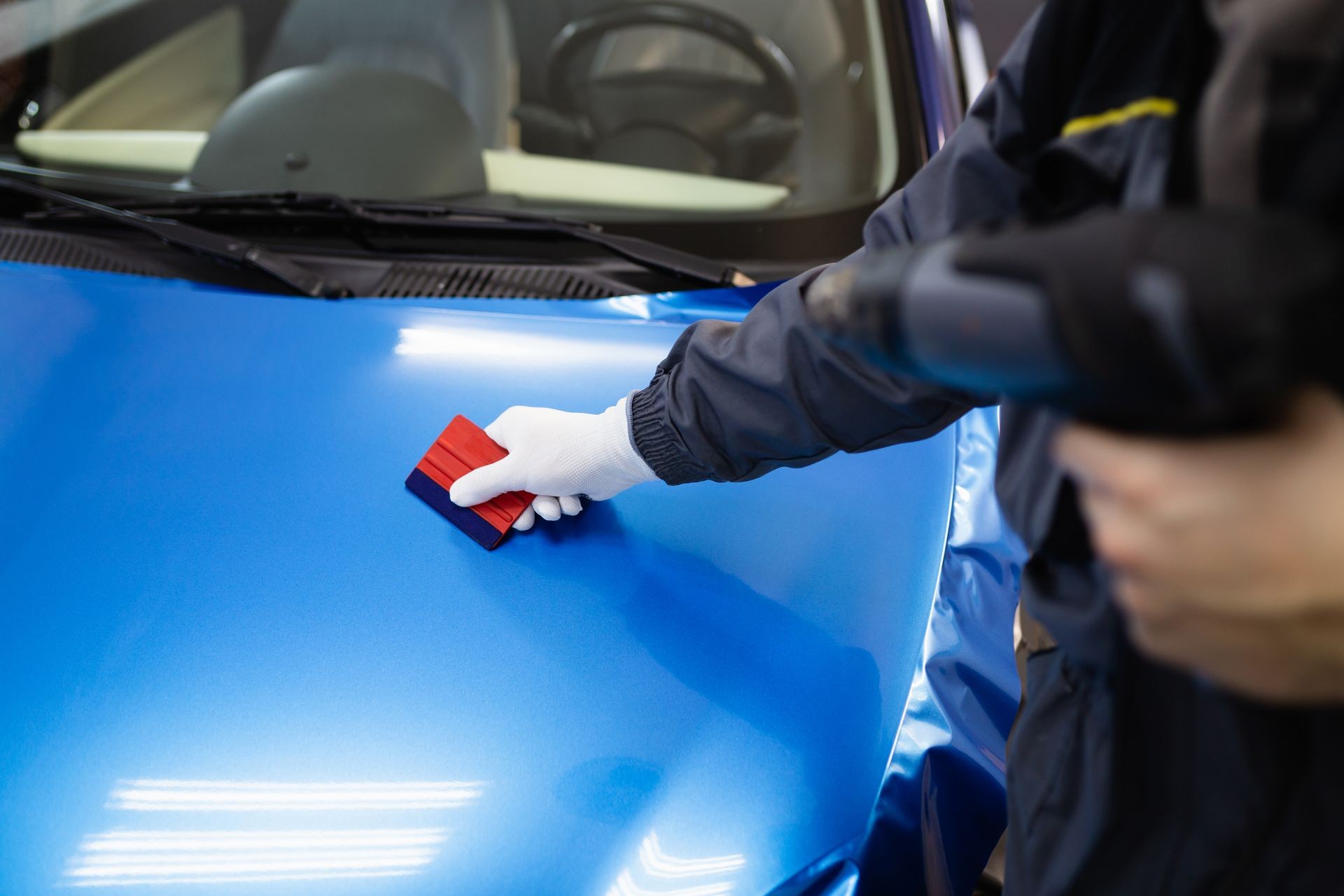 Car wrapping specialist putting vinyl foil or film on car. Selective focus. Car wrapping specialist putting vinyl foil or film on car. Selective focus.